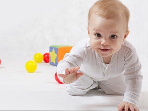 תינוק זוחל קדימה וסביבו צעצועים