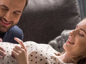 גבר מניח את ידו על בטנה של זוגתו ושניהם מחייכים