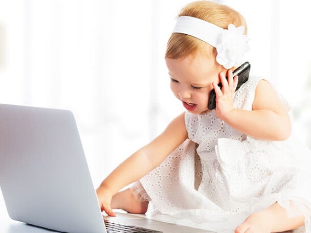 פעוטה מדברת בטלפון ומשחקת במחשב הנייד