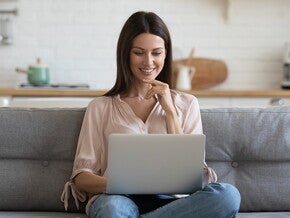 אישה צעירה מביטה מחוייכת במסך המחשב שלה