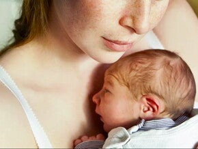 אמא מחזיקה תינוק קטן על חזה