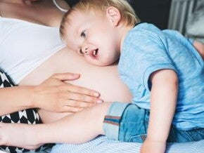 אמא בהריון ופעוט שם את ראשו על ביטנה