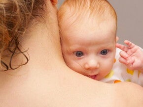 תינוק מציץ מעבר לכתפה של אמו