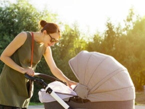 אמא רוכנת לעבר תינוקה הנמצא בעגלה