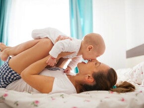 אמא ותינוק משתעשעים יחד במיטה