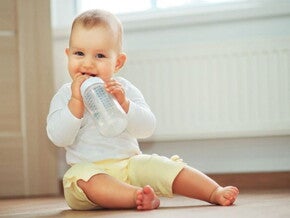 פעוט יושב ושותה מבקבוק