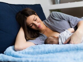 אם שוכבת במיטה ומניקה את תינוקה