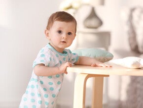 תינוק עומד לצד כיסא