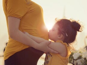 ילד מנשק את אימו ההריונית בבטנה