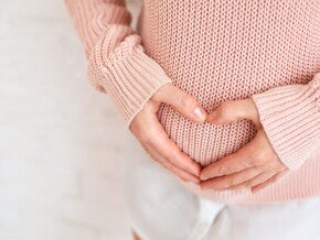 אישה עושה צורת לב על הבטן ההריונית