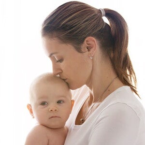 אמא צעירה מנשקת את תינוקה בראשון