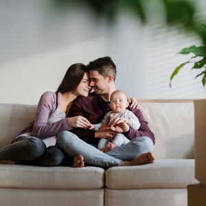 זוג יושב על הספה יחד עם התינוק שלהם, כשהם קרובים ומחייכים