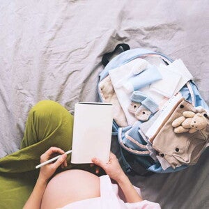 אמא בהריון אוחזת דף עם רשימת קניות לתינוק שיוולד