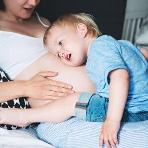 אמא בהריון ופעוט שם את ראשו על ביטנה