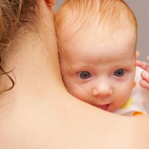 תינוק מציץ מעבר לכתפה של אמו