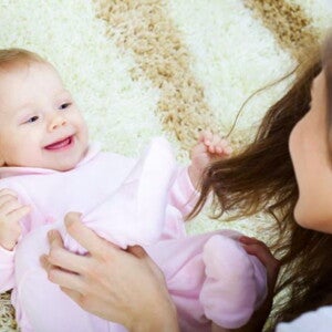 תינוק צוחק לבוש בבגד ארוך עם אימו