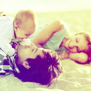 אבא ואמא שוכבים על חוף הים עם תינוקם