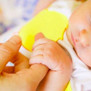 תינוק ישן מחזיק באצבעה של אימו