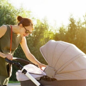 אמא רוכנת לעבר תינוקה הנמצא בעגלה