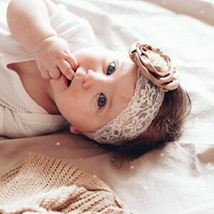 פעוטה שוכבת על גבה עם סרט לראשה