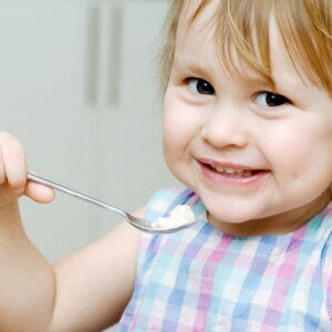 פעוטה אוכלת ומחייכת למצלמה