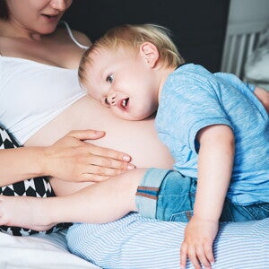 ילד מקשיב לבטן ההריונית של אמו