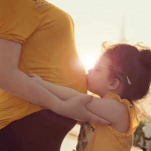 ילד מנשק את אימו ההריונית בבטנה