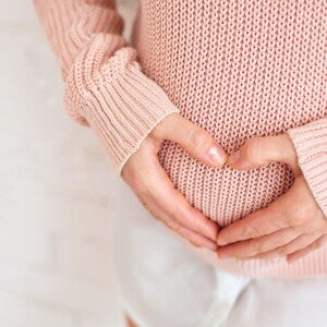 אישה עושה צורת לב על הבטן ההריונית