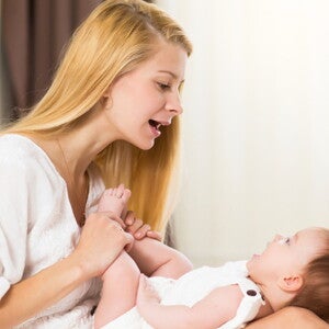 תינוק שוכב על רגליי אימו והיא מדברת אליו