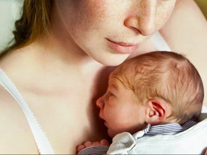 אמא מחזיקה תינוק קטן על חזה