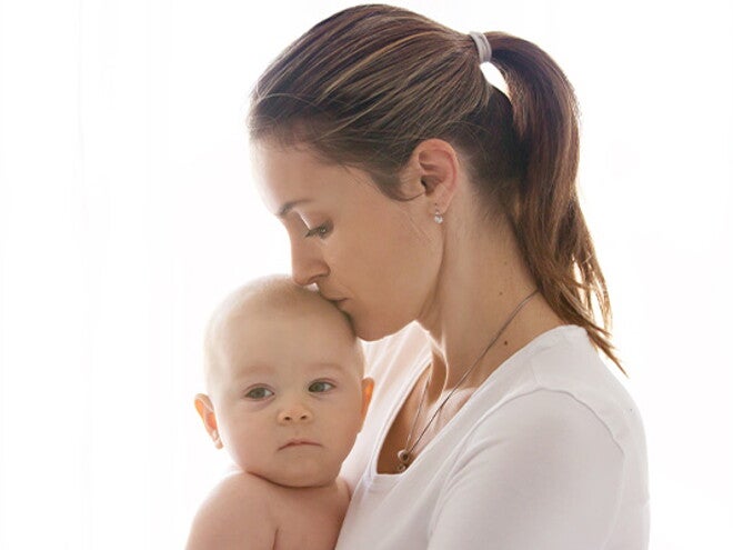 אמא מנשקת את תינוקה בראשו