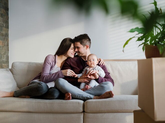 זוג יושב על הספה יחד עם התינוק שלהם, כשהם קרובים ומחייכים