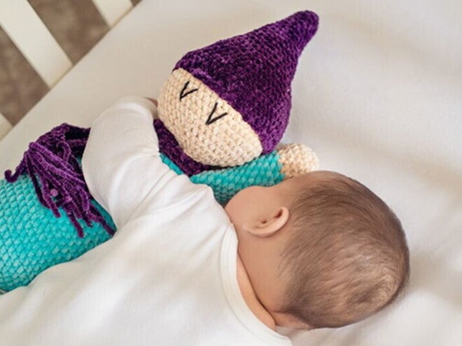 תינוק קטן מחבק בובה רכה במיטתו בעודו ישן