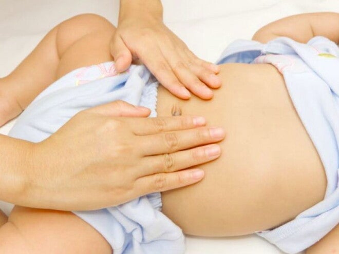 ידי אמא מעסות בטן של תינוק קטן