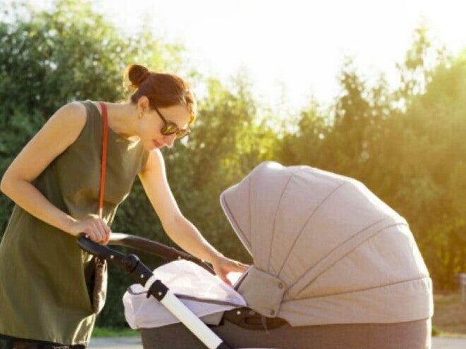 אמא רוכנת לעבר תינוקה הנמצא בעגלה
