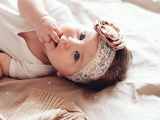 פעוטה שוכבת על גבה עם סרט לראשה