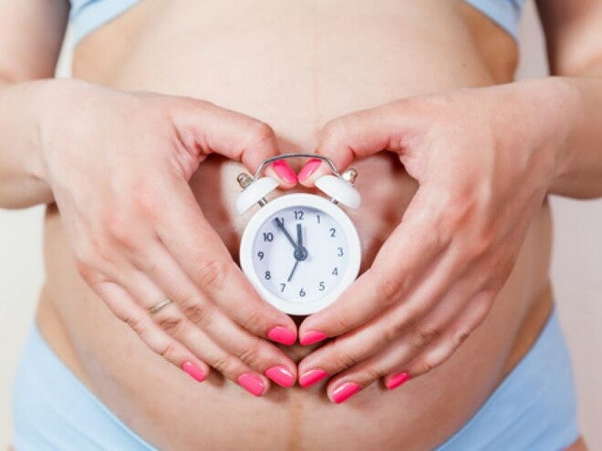 הריונית עם שעון על ביטנה
