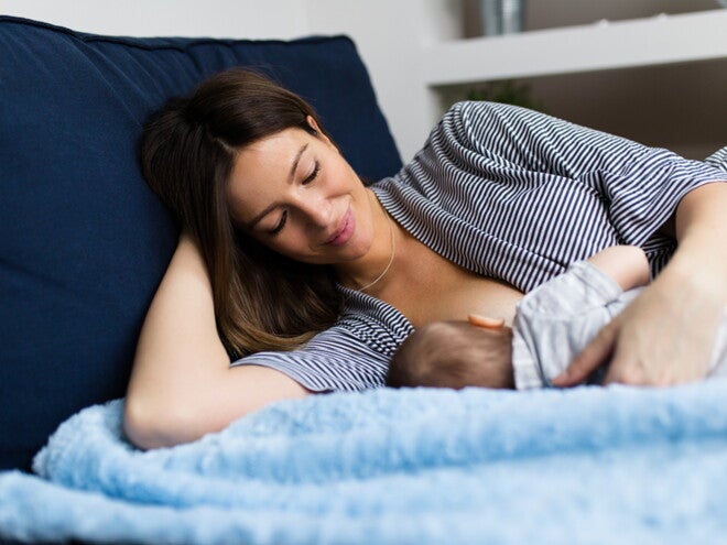 אם שוכבת במיטה ומניקה את תינוקה