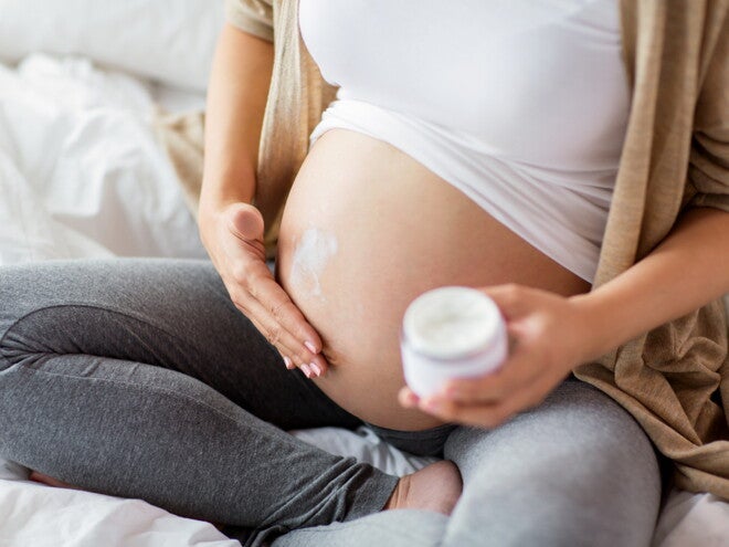 הריונית מורחת קרם על ביטנה