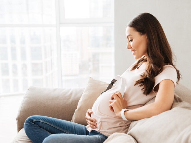 הריונית יושבת על הספה