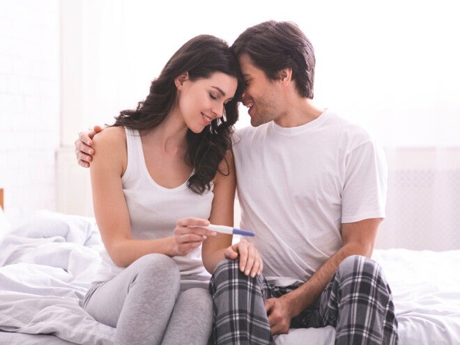 זוג צעיר מחובק ומסתכל על בדיקת הריון