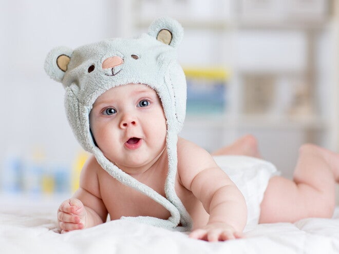 תינוק שוכב על ביטנו עם כובע על הראש