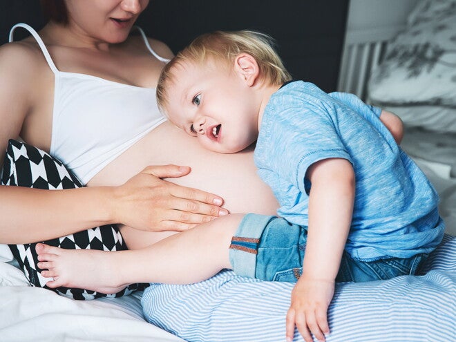 ילד מקשיב לבטן ההריונית של אמו