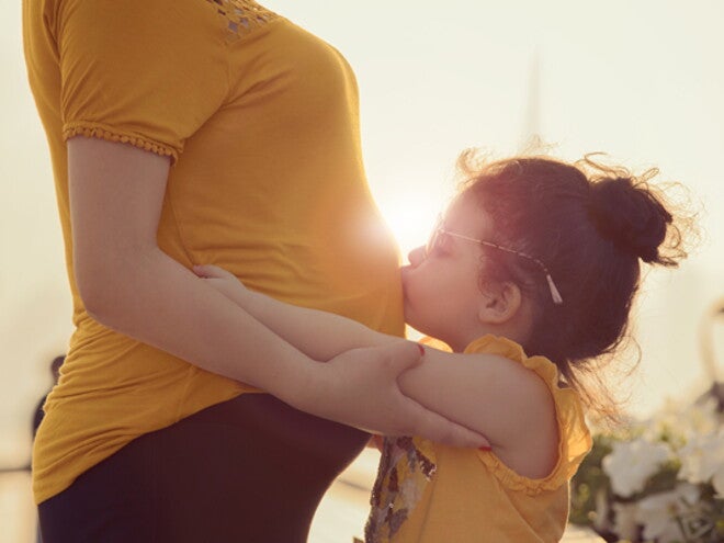 ילד מנשק את אימו ההריונית בבטנה