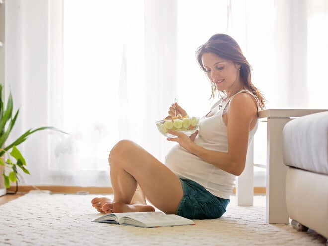 הריונית יושבת ואוכלת פירות