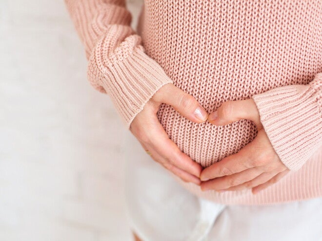 אישה עושה צורת לב על הבטן ההריונית