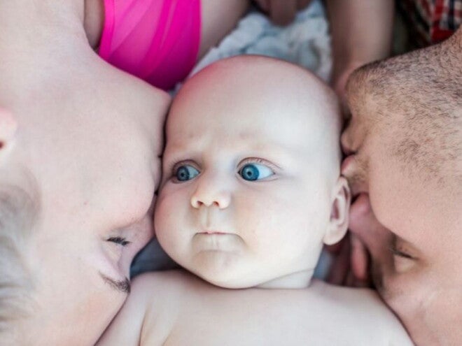 תינוק שוכב במרכז בין שני הוריו
