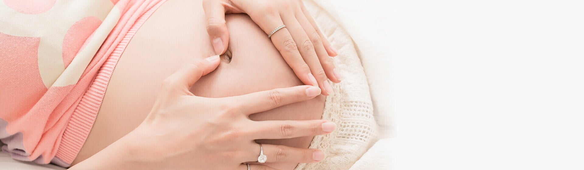 אמא מניחה את ידיה על ביטנה בצורת לב