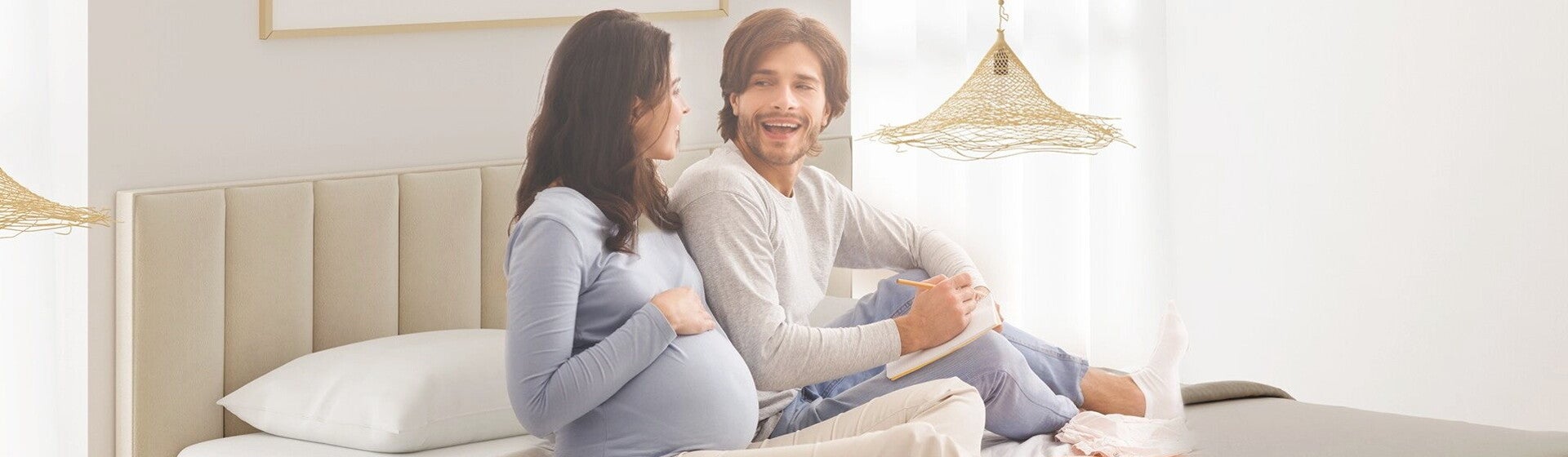 זוג הורים לעתיד יושבים על המיטה וצוחקים