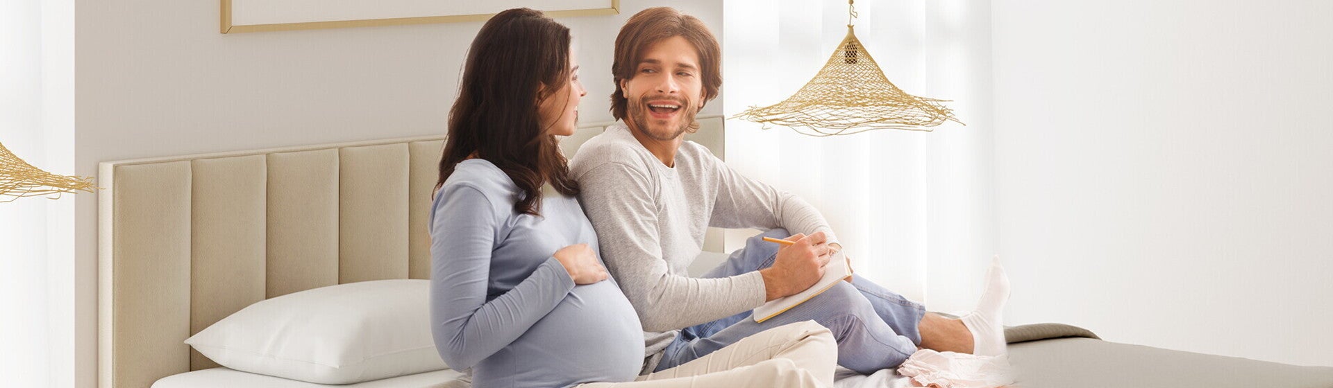 זוג הורים לעתיד יושבים על המיטה וצוחקים